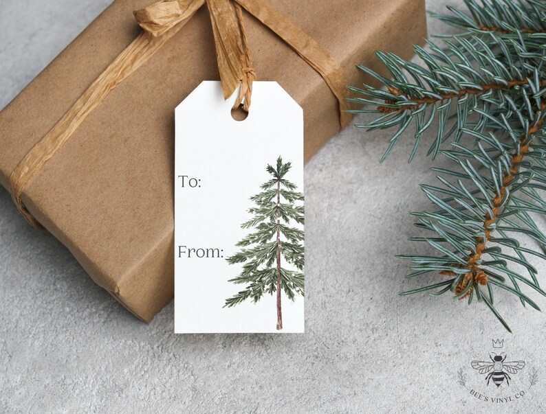 May include: A white gift tag with a watercolor illustration of a pine tree. The tag has the words "To:" and "From:" printed on it.