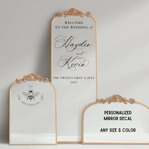 May include: Three ornate gold-framed mirrors with personalized wedding decals. The largest mirror features the names Hayden and Kevin and the date "The Twenty-First of July 2025". The middle mirror has a bee logo with the text "Bee's Vinyl Co.". The smallest mirror has the text "Personalized Mirror Decal Any Size & Color".