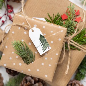 May include: Two brown gift boxes wrapped in white polka dot paper with twine and green sprigs. The top box has a white gift tag with a green watercolor tree and the words "To:" and "From:".