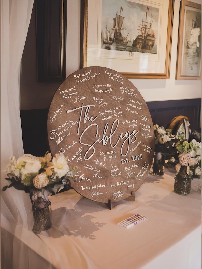 Round wooden wedding guestbook alternative with stand, personalized rustic guest book sign with handwritten wishes, wedding reception table decor with custom engraved names.