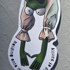 以下が含まれることがあります： 緑色の肌、大きな目、緑色の手でハートを作っている漫画のキャラクターのステッカー。キャラクターはフリルの袖が付いた白い衣装を着ています。テキストは「holding onto my last thread of sanity」と書かれています。