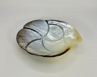 Puede incluir: Un plato de nácar blanco y gris con un diseño de flor tallada.