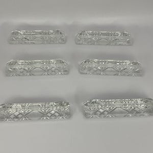 May include: Set of six clear glass napkin rings with a cut glass design.