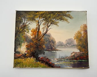 May include: Oil painting of a serene landscape featuring a lake surrounded by trees with autumn foliage. The artwork has a muted color palette with shades of green, brown, and orange. Signed in the lower left corner.