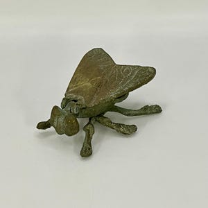 May include: A vintage brass fly shaped trinket box with a hinged lid. The fly has a detailed design and a realistic appearance.