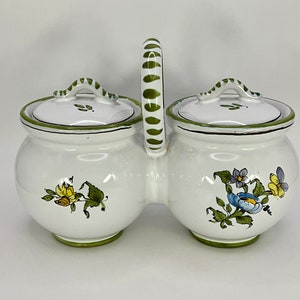 Puede incluir: Jarra doble de cerámica blanca con asa rayada verde y blanca y diseños florales. Las tapas también son blancas con ribete verde.