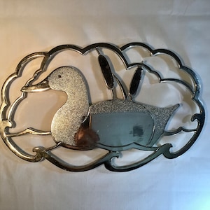 French vintage silver metal trivet stand, it is a duck swimming and some bull rushes behind.