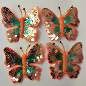 May include: Four iridescent orange and green butterfly-shaped sequins with a beaded center.