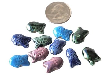May include: Assortment of ten ceramic fish charms in various colors, including blue, green, and purple. Each charm features a detailed fish design with scales and fins.