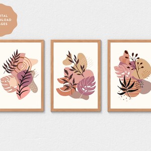 May include: Set of three abstract art prints featuring pink, brown and beige colours with leaf and floral designs. The prints are framed in a light wood frame.