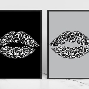 May include: Two framed prints of a pair of lips with a black and white leopard print design. One print has a black background and the other has a grey background.