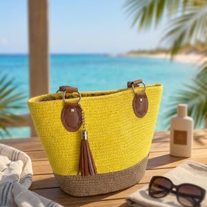May include: A yellow and brown woven tote bag featuring brown leather-like handle attachments, silver-toned metal rings, and a brown tassel accessory. The bag has a wide opening and a structured base, showcasing a two-tone design with a bright yellow upper section and a textured brown lower section.