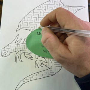May include: A black and white dragon maze with a green circle that says "Mr. T's Puzzles" and "buy now" on it. The maze is on a white sheet of paper with the text "Dragon Maze" and "Copyright 2023 Mr. Pezman's Puzzles" at the top and bottom of the page.