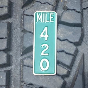 May include: A green and white mile marker sign with the text "MILE 420" on a black tyre.