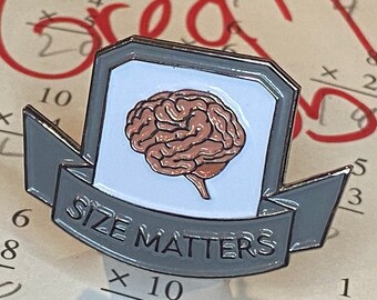 May include: A grey metal pin with a white background and a brown brain illustration. The pin has a banner that reads "Size Matters".