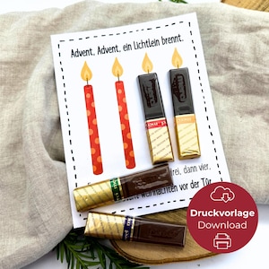 Puede incluir: Una tarjeta rectangular blanca con el texto Advent, Advent, ein Lichtlein brennt. La tarjeta muestra dos velas rojas impresas con llamas naranjas y cuatro barras de chocolate rectangulares con envoltorios dorados como velas.