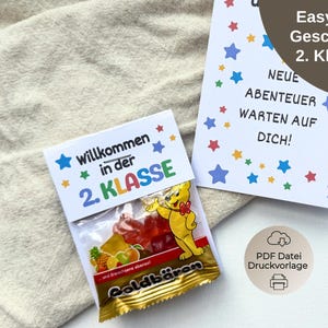 Op de afbeelding: Een cadeauset voor de tweede klas, met een kleine zak gummyberen en een kaart met de tekst "Easy DIY Geschenk 2. Klasse" en "Neue Abenteuer warten auf dich!" in het Duits, versierd met sterren.