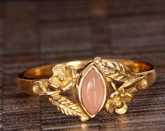 May include: A gold ring with a pink gemstone set in a floral design.