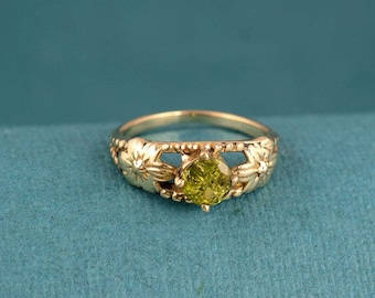 May include: A gold ring with a green gemstone set in a floral design.