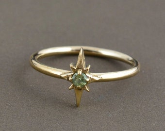 May include: A gold ring with a green gemstone set in a star-shaped design.