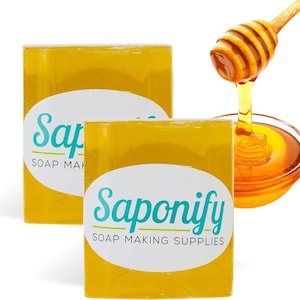 May include: Two yellow soap bars with the text "Saponify Soap Making Supplies" printed on them. A honey dipper is pouring honey into a bowl.