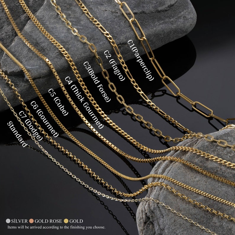 K&ouml;nnte beinhalten: Nahaufnahme von zehn verschiedenen Goldketten-Stilen, darunter eine Paperclip-Kette, eine Figaro-Kette, eine Bold-Forsey-Kette, eine Thick-Gourmet-Kette, eine Cube-Kette, eine Gourmet-Kette, eine Dodge-Kette und eine Standardkette. Die Ketten sind in einer Reihe auf einer grauen Steinoberfl&auml;che angeordnet.