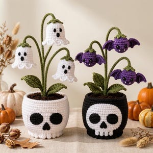 May include: Two crocheted potted plants featuring ghost and bat motifs. The left plant has white ghost-shaped flowers in a white skull pot. The right plant has purple bat-shaped flowers in a black skull pot. Both have green stems and leaves.