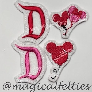 May include: Four felt appliques: two "D" shapes in red and pink, and two Mickey Mouse-shaped balloons in red and pink. All are outlined in white with black stitching details. The text "@magicalfelties" is present.