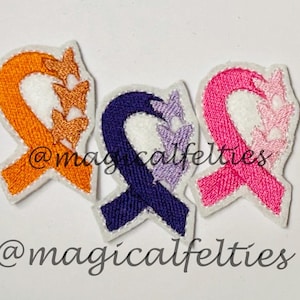 May include: Three felt embroidered ribbon patches with butterfly designs. The ribbons are orange, purple, and pink. The butterflies are in shades of orange, purple, and pink. The patches are for sewing or iron-on application. @magicalfelties