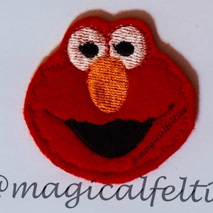 May include: Red felt applique of Elmo, a character from Sesame Street, with a big smile and white eyes. The applique is about 3 inches in diameter.