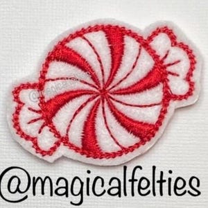 May include: A red and white peppermint candy applique with a stitched design. The candy is in a wrapped shape with a white border. The text "@magicalfelties" is below the candy.