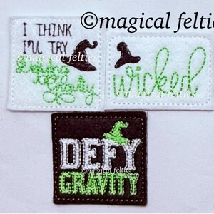 May include: Three felt patches with green and white embroidery. The first patch says "I think I'll try" with a witch's hat. The second patch says "Wicked" with a witch's hat. The third patch says "Defy Gravity" with a witch's hat.