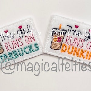 May include: Two white felt patches with embroidered images of coffee cups and text. The first patch says "This girl runs on Starbucks" and the second patch says "This girl runs on Dunkin".
