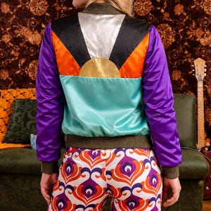 Chaqueta bomber retro de satén con bloques de color: abrigo urbano con patchwork geométrico inspirado en los años 70.