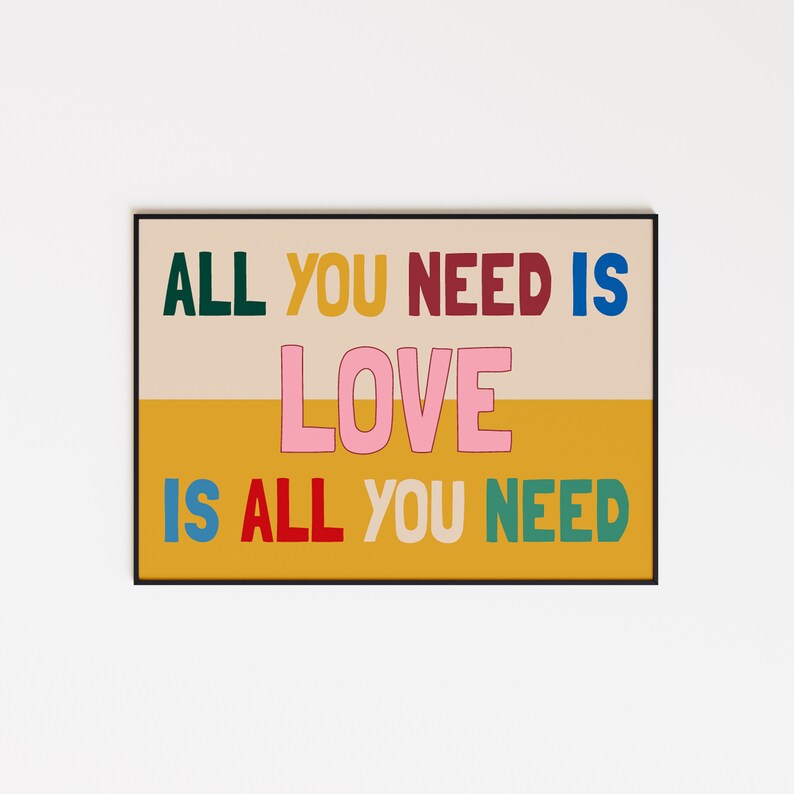 A framed Beatles music print featuring the song lyrics 'All You Need is Love, Love is All You Need' against a beige and yellow background.