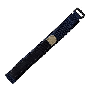 May include: A dark blue nylon watch strap with a black buckle and a tan leather patch with the word "BELLA" embossed on it.