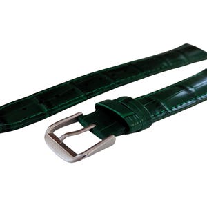 K&ouml;nnte beinhalten: Zwei dunkelgr&uuml;ne Uhrenarmb&auml;nder mit Krokodilhaut-Effekt. Eines der Armb&auml;nder hat eine silberfarbene Schnalle. Die Armb&auml;nder sind aus gl&auml;nzendem Material gefertigt und werden an einem Zifferblatt befestigt.