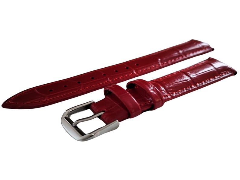 K&ouml;nnte beinhalten: Ein Paar rote Uhrenarmb&auml;nder mit gl&auml;nzendem Finish und Krokodilleder-Textur. Ein Armband hat eine silberne Schnalle. Die Armb&auml;nder sind zur Befestigung an einem Zifferblatt konzipiert. Die Armb&auml;nder sind neu.