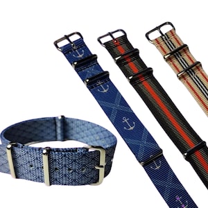 May include: A collection of watch straps in various designs. One strap is a blue pattern with a silver buckle. Three additional straps feature nautical and striped patterns in blue, black, and beige with silver hardware.