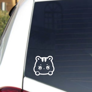 Könnte beinhalten: Weißer Vinyl-Aufkleber mit einem Cartoon-Tier mit großen Augen und einem überraschten Ausdruck. Das Tier schaut nach vorne und hat die Arme vor sich verschränkt.