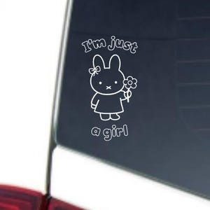 May include: White vinyl decal featuring a cartoon bunny holding a flower, with the text "I'm just a girl". The bunny has a bow on its head and is wearing a dress. The decal is likely for a car window or similar surface.