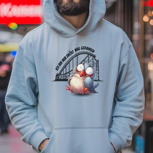 Könnte beinhalten: Hellblauer Hoodie mit einem Cartoon-Vogel auf einer Achterbahn. Der Text auf dem Hoodie lautet "Ich bin nur drolf mal gefahren".