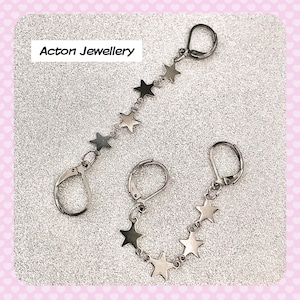 May include: A pair of silver star charm earrings. Each earring has a silver hook and a chain of silver stars.
