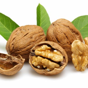 May include: Four walnuts, two with shells and two without, with green leaves in the background.