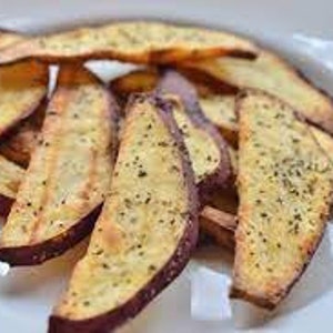 Op de afbeelding: Een bord met gebakken zoete aardappel frietjes, gekruid met kruiden en specerijen.