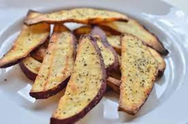 Op de afbeelding: Een bord met gebakken zoete aardappel frietjes, gekruid met kruiden en specerijen.