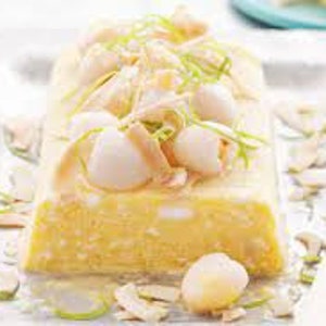 May include: A yellow and white layered dessert with a creamy texture, topped with lychees, shredded coconut, and green onions.