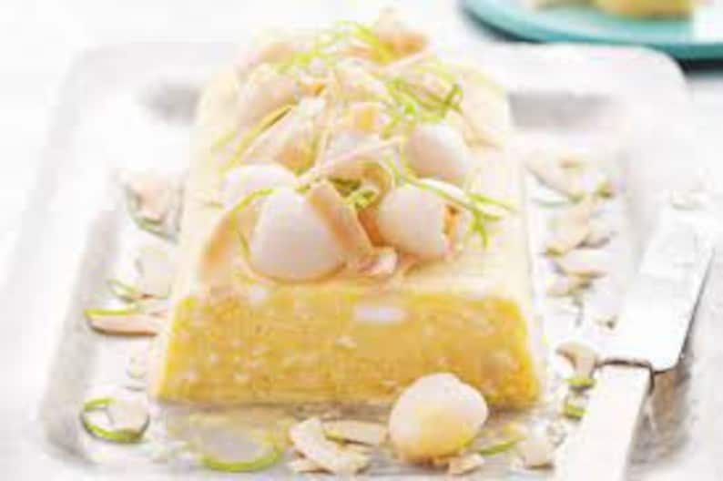May include: A yellow and white layered dessert with a creamy texture, topped with lychees, shredded coconut, and green onions.