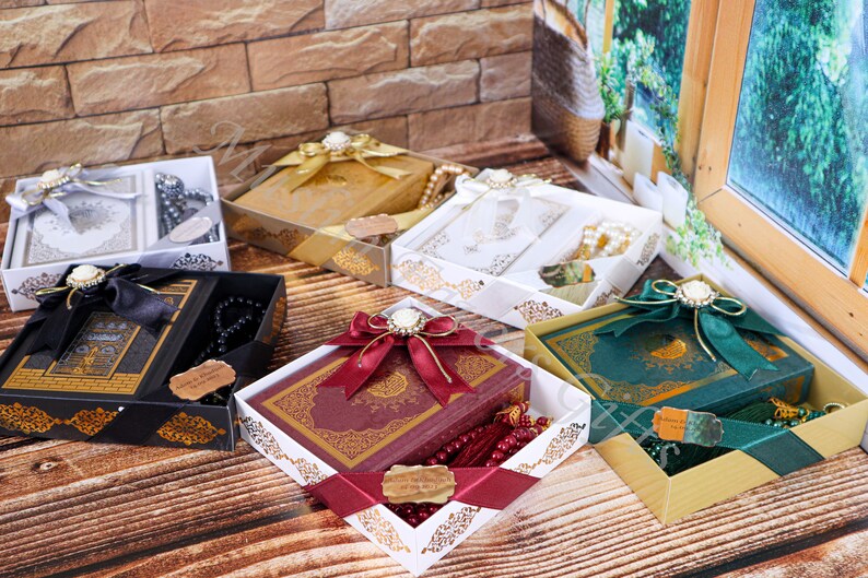 May include: Assortment of gift boxes containing prayer books and prayer beads. The boxes are decorated with ribbons and bows. The prayer books are in different colors, including black, red, green, and white. The prayer beads are in different colors, including black, red, and white.