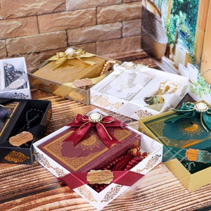 K&ouml;nnte beinhalten: Sortiment von Geschenkboxen mit Gebetsb&uuml;chern und Gebetsperlen. Die Boxen sind mit B&auml;ndern und Schleifen verziert. Die Gebetsb&uuml;cher sind in verschiedenen Farben, darunter Schwarz, Rot, Gr&uuml;n und Wei&szlig;. Die Gebetsperlen sind in verschiedenen Farben, darunter Schwarz, Rot und Wei&szlig;.